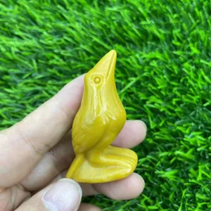 Handheld yellow gemstone carved raven crystal bird figurine detail view close up display