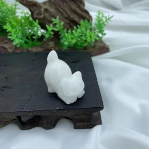 Close-up detail view of the hand-carved natural crystal cat figurine resting on dark wood.