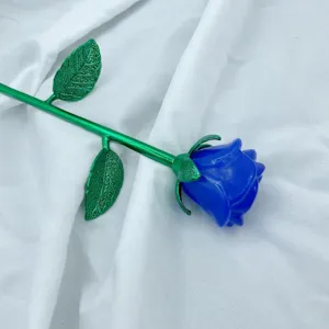 Dettaglio di rosa in cristallo con fiore blu e stelo verde su sfondo in tessuto.