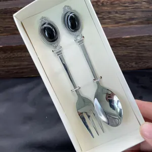 Dettaglio del set cucchiaio e forchetta in pietra preziosa vintage con manici intagliati e pietre.