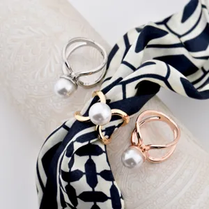 Close-up detail of elegant pearl scarf rings set, featuring shiny alloy metal bands and glossy pearls.