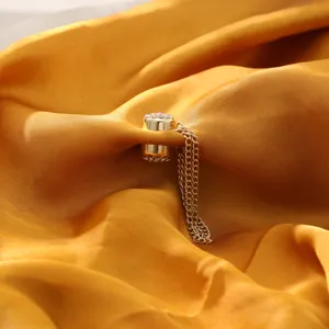 Close-up detail of a golden rhinestone magnetic clothing clip with delicate hanging chains.