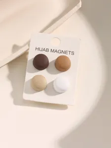 Gedetailleerde close-up van een set van vier aardekleurige magnetische hijabspelden op kaart.