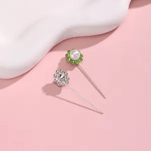 Close-up detail van prachtige zilveren lange sjaalspeld met parel en groene strass.