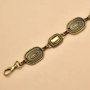 Close-up detail of vintage bronze metal chain belt with textured rope links and lobster clasp.