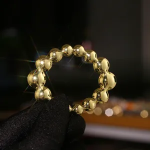 Glossy gold-tone spherical bead U-shaped scarf buckle detail, elegant accessory.