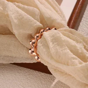 Rose gold scarf buckle detail view showing glossy metal bead design on soft beige gauze fabric.
