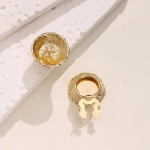 Detailed close-up of gold-plated shirt button covers featuring swirl texture and sparkling zirconia.