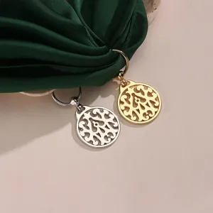 Detailed shot of gold and silver alloy hollow silk scarf buckle with green silk fabric.