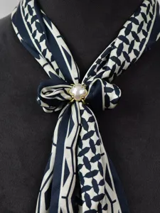 Close-up detail of a chic black and white patterned silk scarf tied with a clover pearl rhinestone buckle.