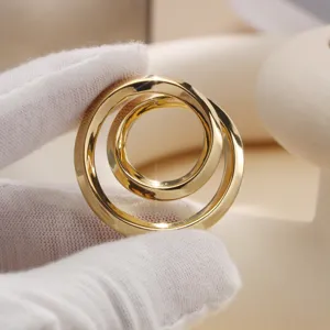 Close-up view of the golden interlocking scarf buckle detail, showing its smooth metallic finish.