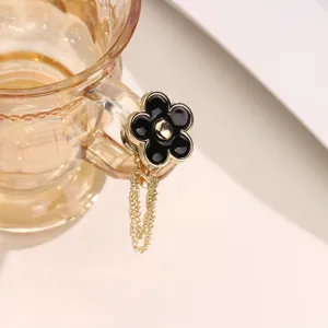 Close-up detail of the elegant camellia magnetic waist buckle with stylish hanging chain accessory.