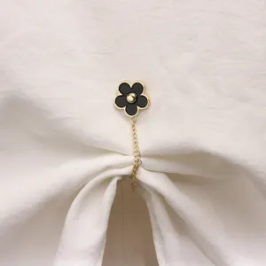 Detailed close-up of a chic black and gold camellia flower magnetic clothing buckle accessory.