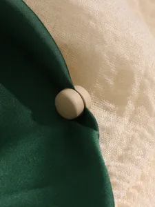 Close-up detail van matte ronde magnetische broche en sjaalclip accessoire, elegante stof.