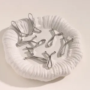 Vue de detail de pinces a hijab en metal argente et clips de taille sur un plateau blanc.