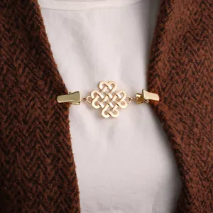 Vue détaillée d'un clip de pull nœud chinois doré, élégante attache de cardigan en métal.