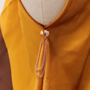 Detailaufnahme der roségoldenen magnetischen Kleiderklammer mit doppelten Ketten auf Textil.