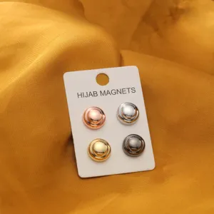 Nahaufnahme von vierfarbigen runden Hijab-Magneten auf weißer Displaykarte vor Satinhintergrund.