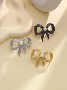 Primo piano di eleganti clip per sciarpa fiocco perla strass in tre colori metallici.