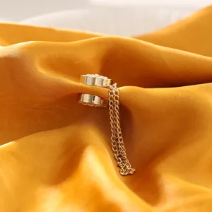 Gedetailleerde close-up van gouden magnetische gesp met fijne ketting en cameliemotief.