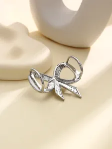 Dettaglio anello per sciarpa a fiocco argento, design elegante in metallo per decorazione.