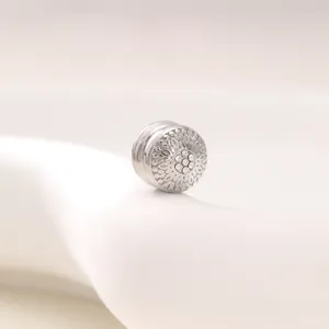 Detailed view of round vintage magnetic scarf clip featuring carved design and sparkling stones.