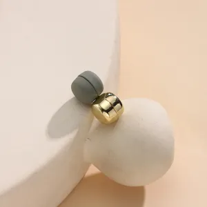 Gedetailleerde close-up van minimalistische magnetische hijab-spelden in grijs en goud.