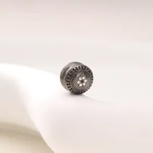 Detailed close-up of a vintage round magnetic scarf buckle with intricate hollow carved patterns.