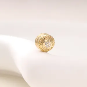 Close-up of golden magnetic scarf clip with delicate vintage filigree pattern and clear rhinestones.