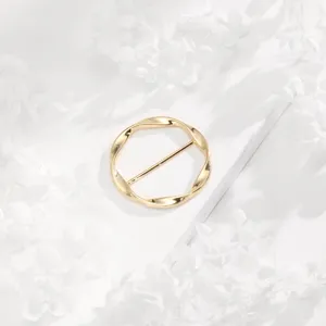 Gold twisted circular scarf buckle detail, elegant metal clothing corner ring accessory.