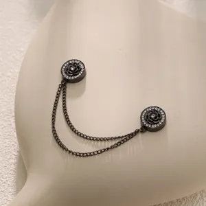 Gedetailleerde close-up van strass camelia, dubbele ketting, elegante zwarte metalen accessoire.