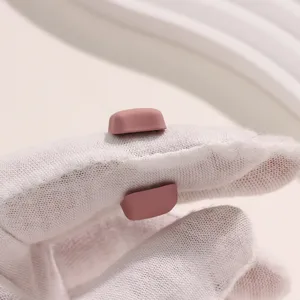 Detailweergave van kleine roze matte hijab-magneten op witte handschoenen getoond.