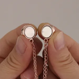 Close-up detail of round magnetic scarf buckle in rose gold with delicate chain accessory.