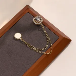 Gouden magnetische kledingbroche met vierkante strass steen en dubbele ketting op display tray