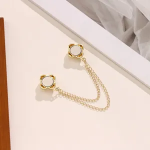 Gold magnetic clothing clip with double chain quatrefoil design for secure waist adjustment.