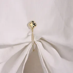 Detail shot of a golden clover magnetic clothing clip with delicate chain for stylish waist up.