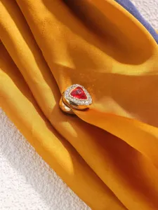 Close-up of a triangular magnetic scarf buckle, sparkling rhinestones, gold finish.