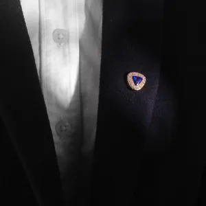 Close-up detail of stylish triangular magnetic brooch featuring blue stone and sparkling crystals.