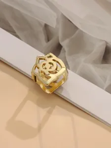 Vergoldete ausgehöhlte Kamelien-Tuchschließe im Detail, elegantes Metallaccessoire für Damen.