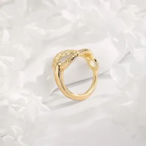 Close-up view of a gold metal scarf ring buckle, showing its delicate textured design and smooth finish.