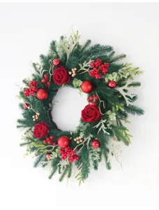 Detailed view of artificial Christmas wreath with red roses and berries for door decor.