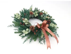 Weihnachtskranz Dekoration mit Tannennadeln Eukalyptoblättern Zapfen und brauner Schleife.