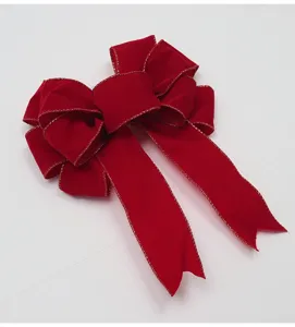 Primo piano dettagliato di un fiocco di Natale in velluto rosso con bordo dorato.
