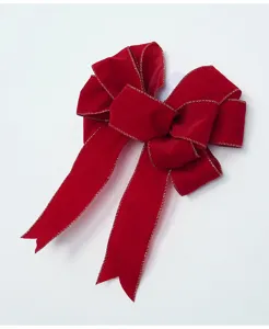 Dettaglio fiocco di Natale in velluto rosso, decorazione appendiabiti albero oro.