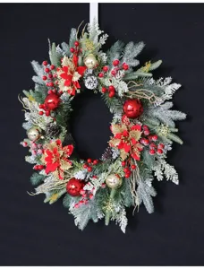 Detailed close up of artificial Christmas wreath with frosted pine needles and red berries.