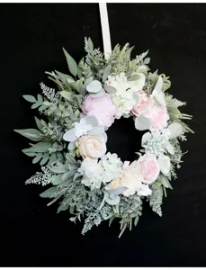 Close up of artificial peony and rose floral wreath detail with lush greenery and elegant ribbon.