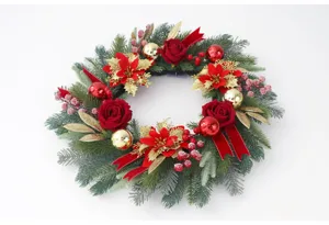 Beautiful Christmas wreath with red roses, gold poinsettia and berries for holiday door decor.