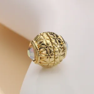 Close-up detail of golden magnetic clasp with textured grid pattern and AB crystal ends.