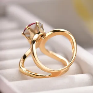 Gold-tone split band ring with red crystal design, elegant modern fashion accessory.