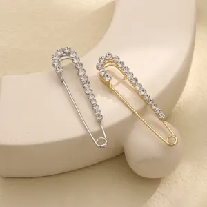 Dettaglio ravvicinato di squisite spille di sicurezza con strass in argento e oro.